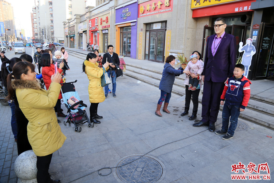 過路市民爭相與“巨人”合影。