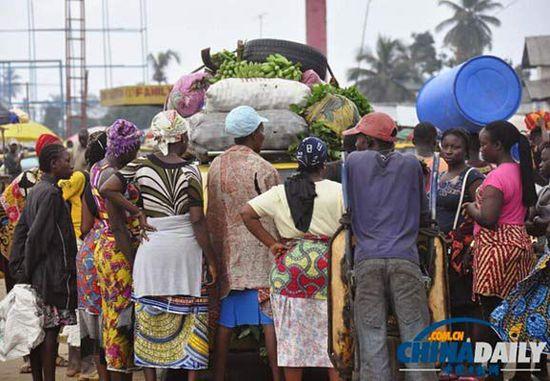 當(dāng)?shù)貢r(shí)間2014年8月14日，利比里亞蒙羅維亞，市場(chǎng)里的商人們圍著一輛汽車(chē)。