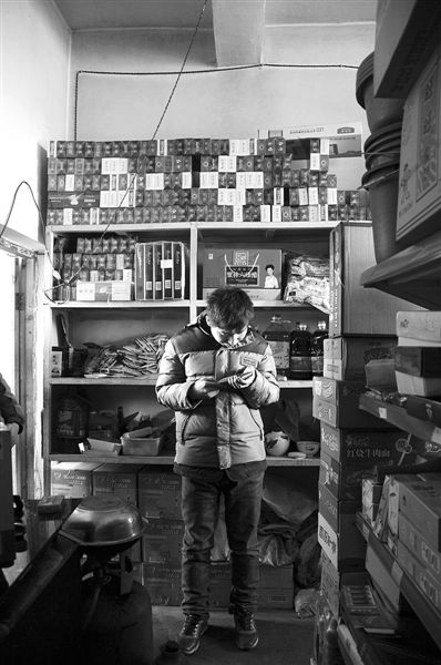 1月21日，周瑋在自家的超市里玩計(jì)算器。