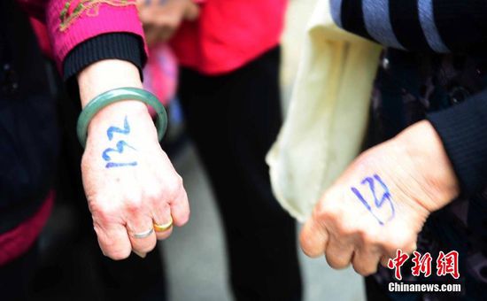 圖為10月28日，在江西九江市一家羊絨皮草服裝服飾博覽會現(xiàn)場，老人們正在頂著寒風排隊等待領取10元代金劵。