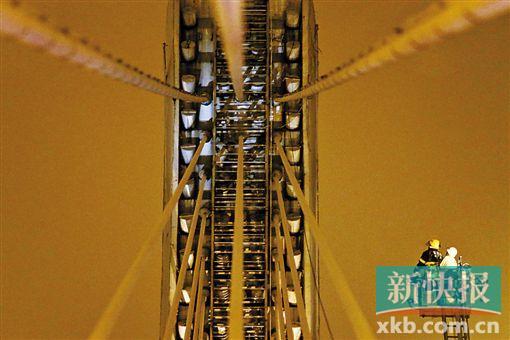 截至今日零時(shí)，男子仍未有下橋舉動(dòng)。圖為公安和消防人員乘消防云梯在高空上和男子交談。